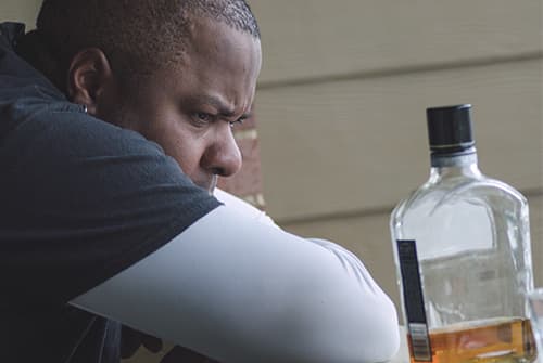 Man looking intently at bottle of alcohol, struggling with alcoholism