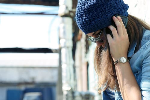 woman quietly talks on phone to narcotic helpline