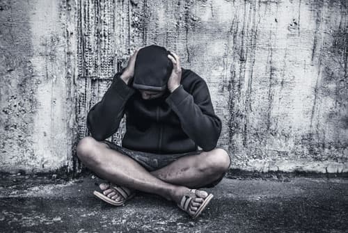upset heroin addict sitting on ground