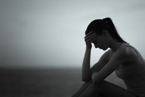 Silhouette of woman on floor in dark room experiencing roxicodone effects