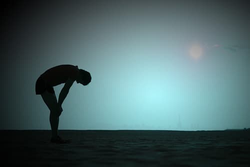 silhouette of man tired with hands on knees
