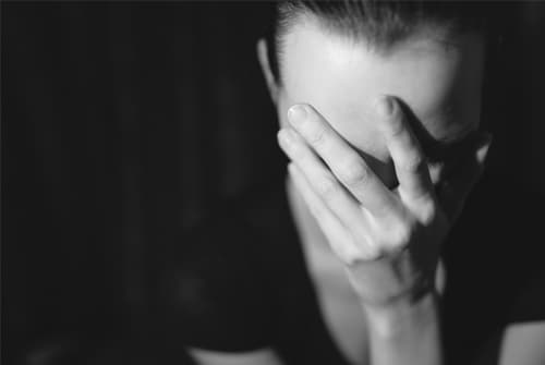 woman with hand over face in dark