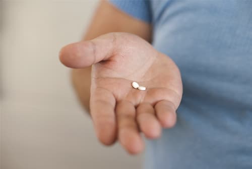 Man holds out hand with dexedrine pills