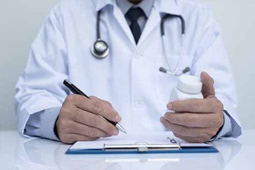Doctor writes notes and holds bottle of suboxone pills